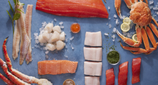 Flat lay of multiple species of Alaska seafood, including Dungeness Crab, King Crab, Salmon and Scallops.